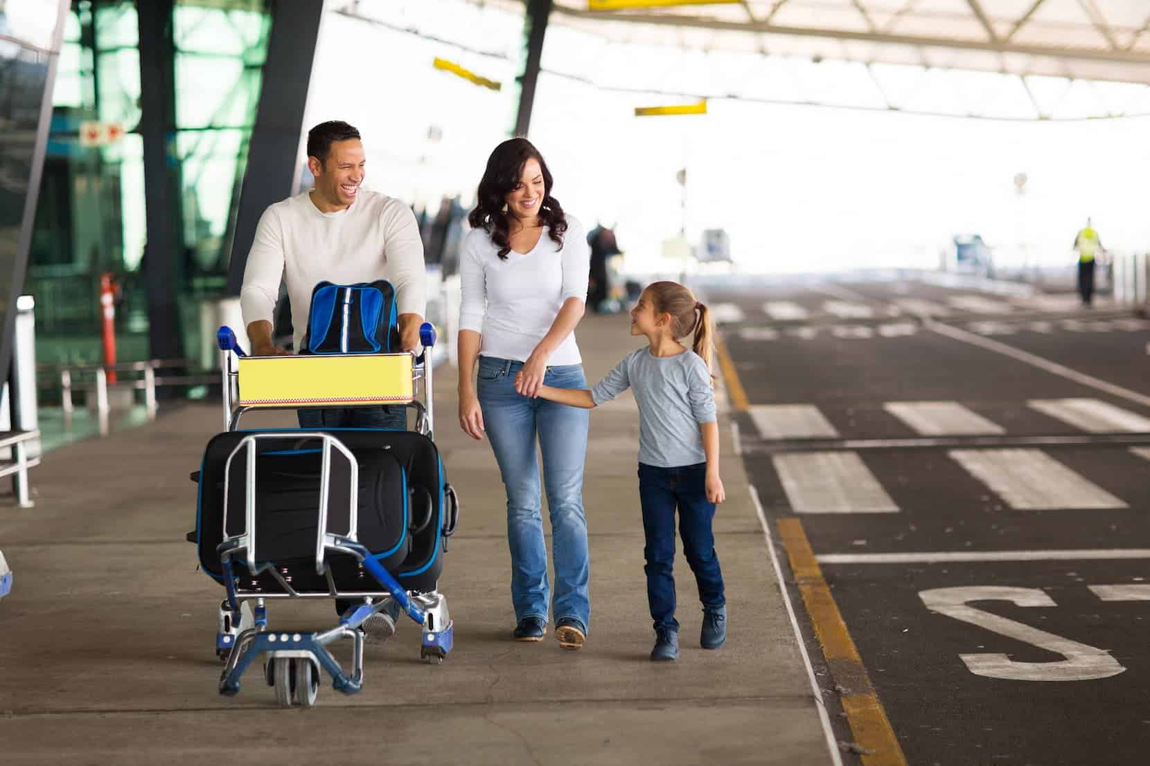Happy family walking through an airport terminal with luggage, representing hassle-free travel access from Morgan Maples Estates.