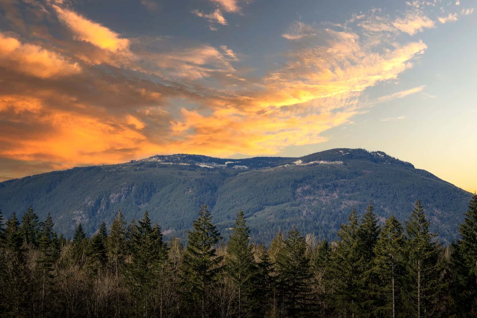 Sunset sky over forested mountains near Chemainus, BC, showcasing the natural beauty surrounding Morgan Maples Estates.