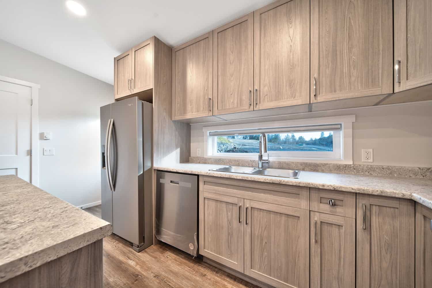 Close-up of the Westholme kitchen featuring wood cabinets, stainless steel appliances, and a wide window over the sink.