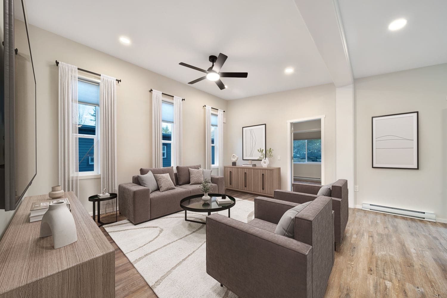 Furnished living room in the Westholme home with brown armchairs, modern ceiling fan, and tall windows with curtains.