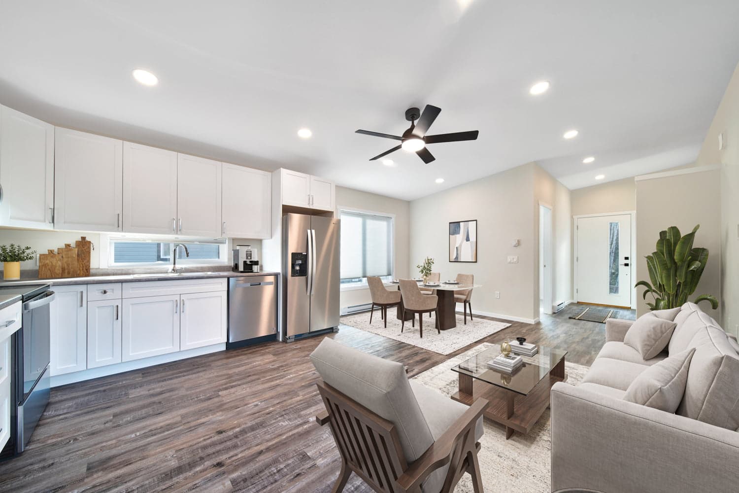 Modern open-concept kitchen and living room with wood flooring and stainless steel appliances, showing a customizable home interior.